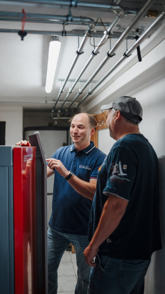 Zwei Installateure besprechen eine Heizungsanlage im Technikraum