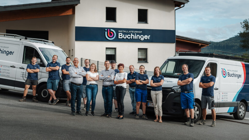 Das Team von Installateurhof Buchinger vor dem Firmengebäude mit den Firmenfahrzeugen
