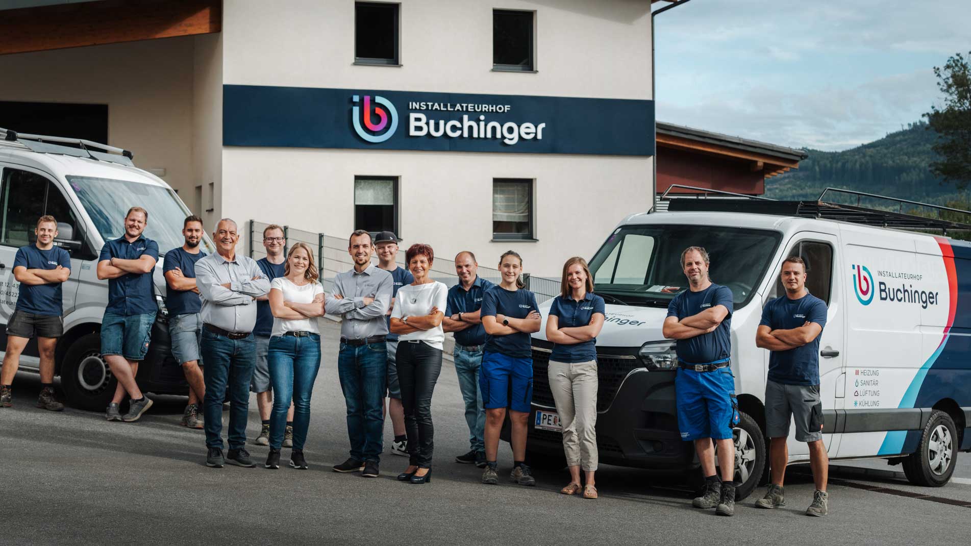 Das Team von Installateurhof Buchinger vor dem Firmengebäude mit den Firmenfahrzeugen